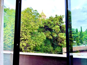 Blick durch ein Fenster auf ein Gebäude im Hintergrund mit einer Kuppelstruktur.