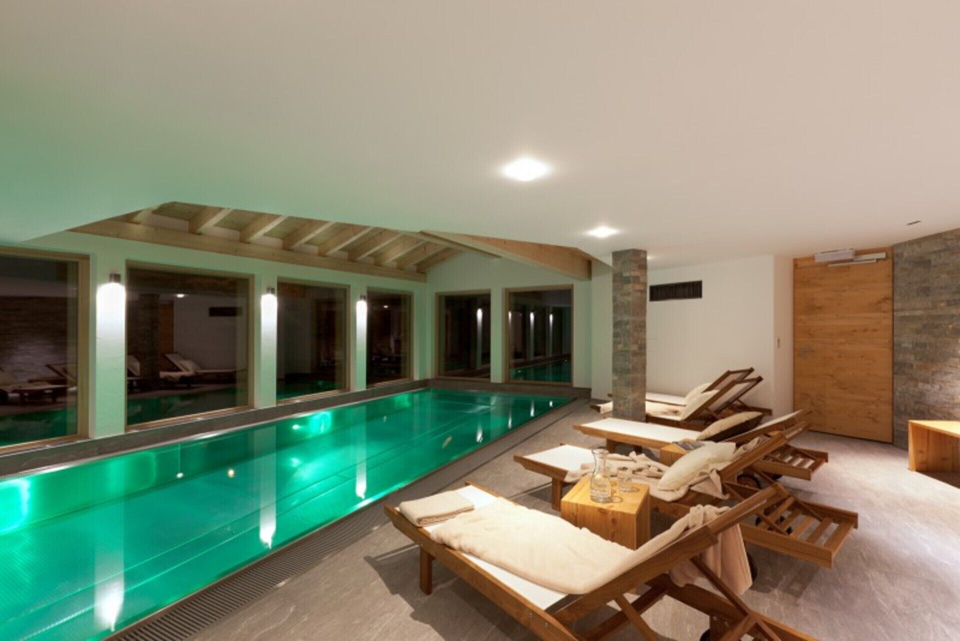 Un espace piscine avec des chaises longues et un banc en bois.
