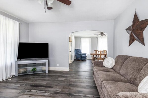 A living room with a flat-screen TV, a sofa, a dining table with chairs, and a star decoration on the wall. - Charming 4 BdRm Home (Shullsburg)
