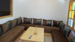 Een moderne woonkamer met een bruine modulaire bank, een houten salontafel en decoratieve kussens.