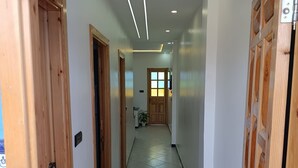 Een gang met houten deuren, een betegelde vloer en inbouwverlichting.