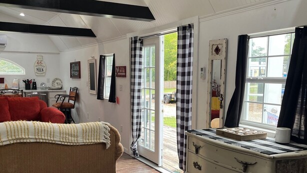 A spacious room with a large bed, a dresser, and a window with curtains.