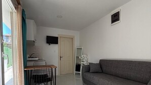A living room with a sofa, a coffee table, a TV mounted on the wall, and a dining area with a table and chairs. - Marmaris apartment with pool (Armutalan)