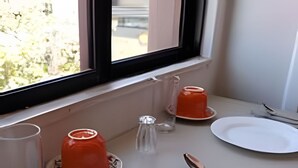A neatly set dining table with plates, cutlery, and glasses, positioned near a window.