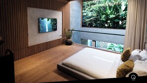 A modern bedroom with a large window, a bed, a TV, and a potted plant.