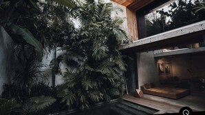A modern house with a large indoor garden, a wooden deck, and a cozy seating area.