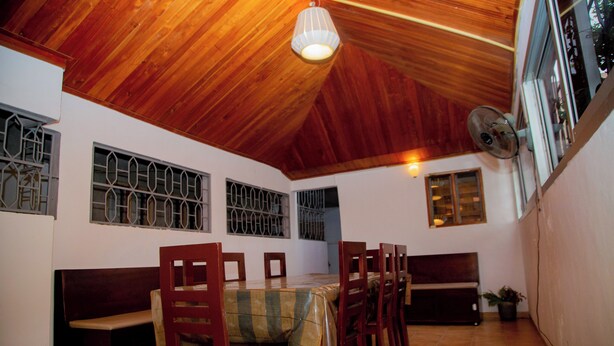Un comedor con techo y paredes de madera, una mesa con sillas y un banco.