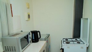 Una kitchenette equipada con microondas, cafetera y cocina a gas.