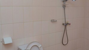 Un baño con inodoro, ducha y soporte para papel higiénico.