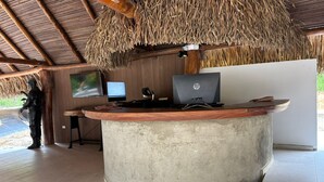 A reception desk with a concrete base, a wooden counter, and a thatched roof overhead. - hacienda hotel texas (Durania)