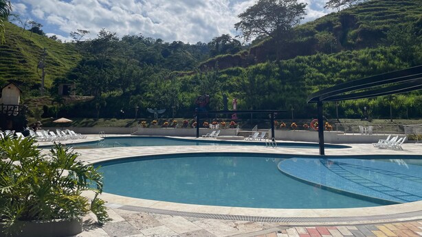 A pool area with lounge chairs and a view of a lush green hillside. - hacienda hotel texas (Durania)