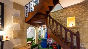 A cozy interior with a wooden staircase, stone walls, and a small play area with toys.