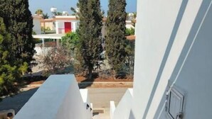 Un couloir étroit aux murs blancs, doté d’un sol carrelé, mène à une porte rouge.