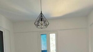 Une petite chambre propre, avec deux lits simples, une table de chevet et un luminaire suspendu.