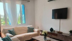 Un salon avec un canapé, une table basse et un téléviseur.