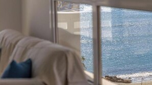 Ein Zimmer mit großem Fenster und Blick auf einen Strand.