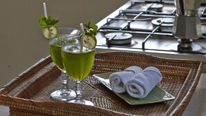 A tray with two glasses of green beverage, a plate with rolled towels, and a gas stove.