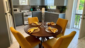 Uma cozinha moderna com armários cinza, fogão branco e uma mesa de jantar com cadeiras e guardanapos amarelos.