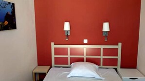 A hotel room with a red accent wall, a white bed with a single pillow, two bedside tables, and two wall-mounted lamps. - Superb duplex Cap Esterel Sea view (Saint-Raphaël)