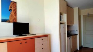 A compact kitchen with a television on a cabinet, a refrigerator, and a microwave. - Superb duplex Cap Esterel Sea view (Saint-Raphaël)