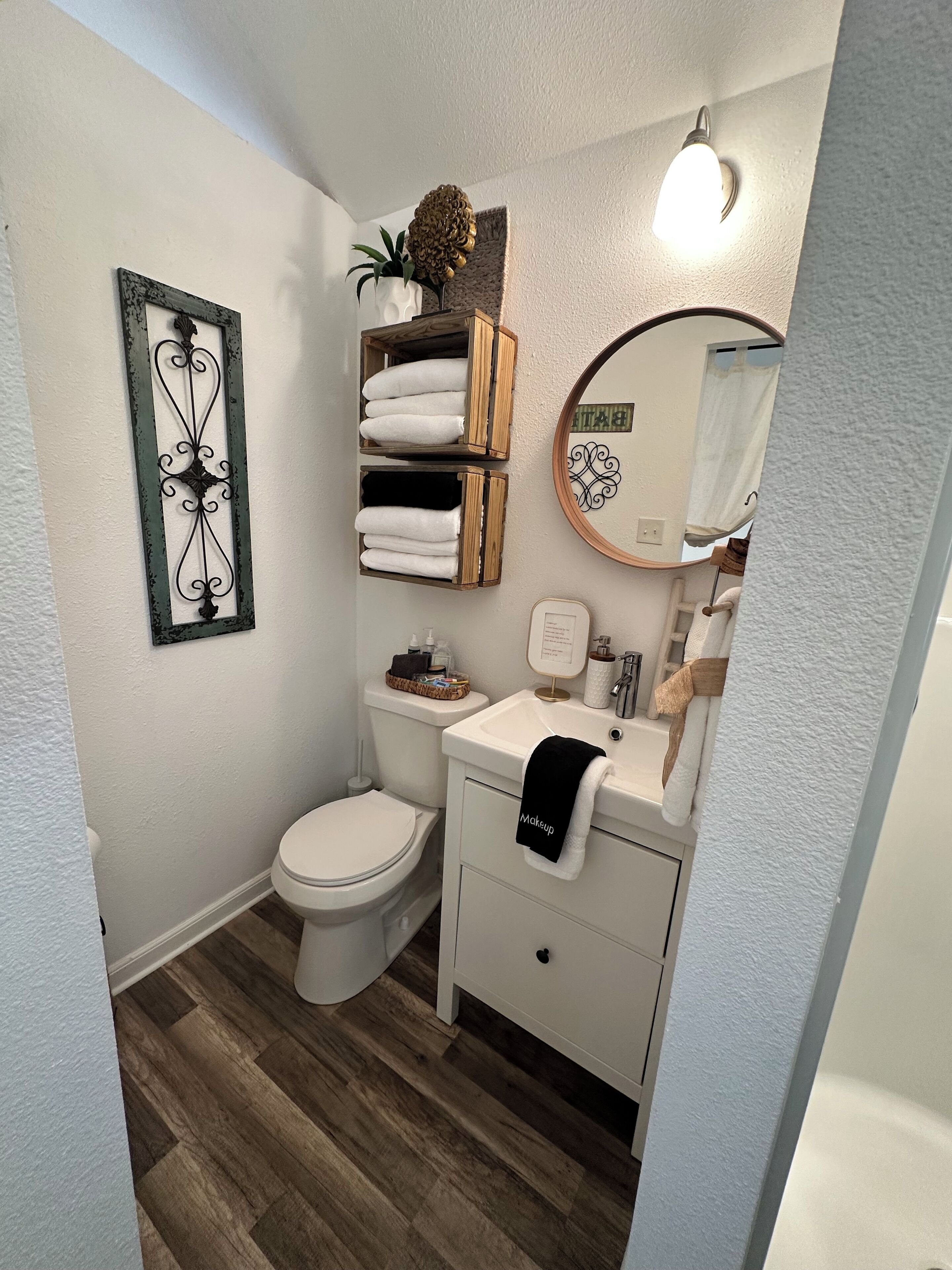 Une petite salle de bain comprenant des toilettes, un lavabo et des étagères de rangement.