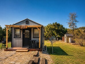 A cabin with a porch, a sign reading 'CABIN,' and a windmill in the background.