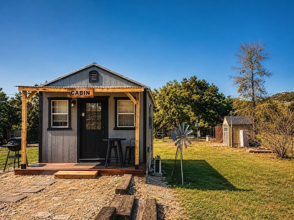 A cabin with a porch, a sign reading 'CABIN,' and a windmill in the background.