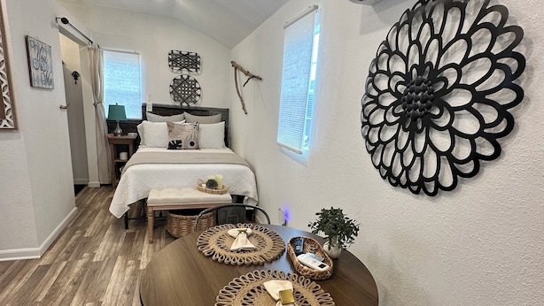Une chambre d’hôtel de taille réduite, comprenant un lit, une table de chevet et un coin repas avec une table et des chaises.