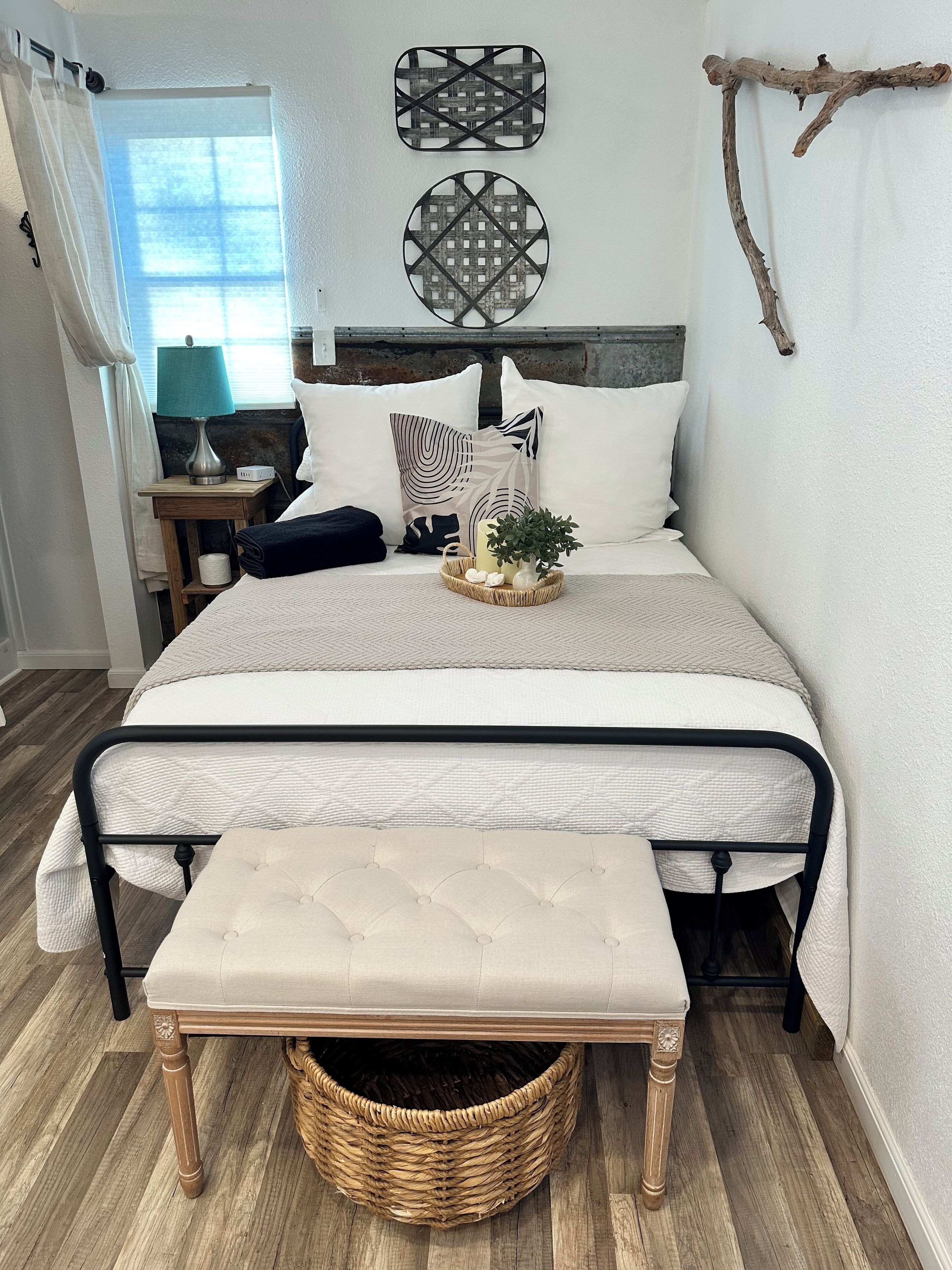 A neatly arranged bedroom with a bed, bedside table, lamp, and a small bench.