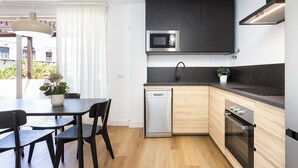 Eine moderne Küche mit Geschirrspüler, Mikrowelle und Backofen. Ein Esstisch mit Stühlen und einem Blumentopf sind ebenfalls vorhanden.