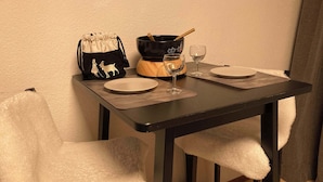 A dining table with two plates, a wine glass, a black bag with a white design, and a wooden bowl with a spoon.