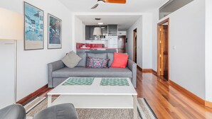 Una sala de estar moderna con un sofá gris, una mesa de centro blanca y un ventilador de techo.