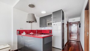 Una cocina moderna con encimera roja, electrodomésticos de acero inoxidable y una estructura de vidrio.