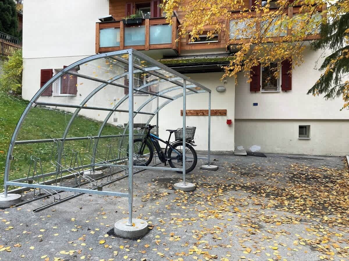 Un abri à vélos couvert, doté d’une structure métallique et contenant un vélo.