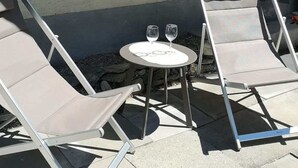 Two lounge chairs, a small round table with two wine glasses, and a window with a patterned curtain. - Cozy Zermatt Studio: Terrace, Village Views (Zermatt)