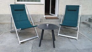 Two green lounge chairs and a small round table on a concrete patio. - Studio Alpine Zermatt: Village views & Terrace (Zermatt)