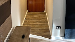Un pasillo con una puerta de madera, un teléfono y un enchufe.
