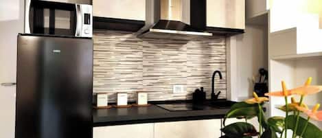 Una cocina moderna con microondas integrado, electrodomésticos de acero inoxidable y salpicadero de azulejos.