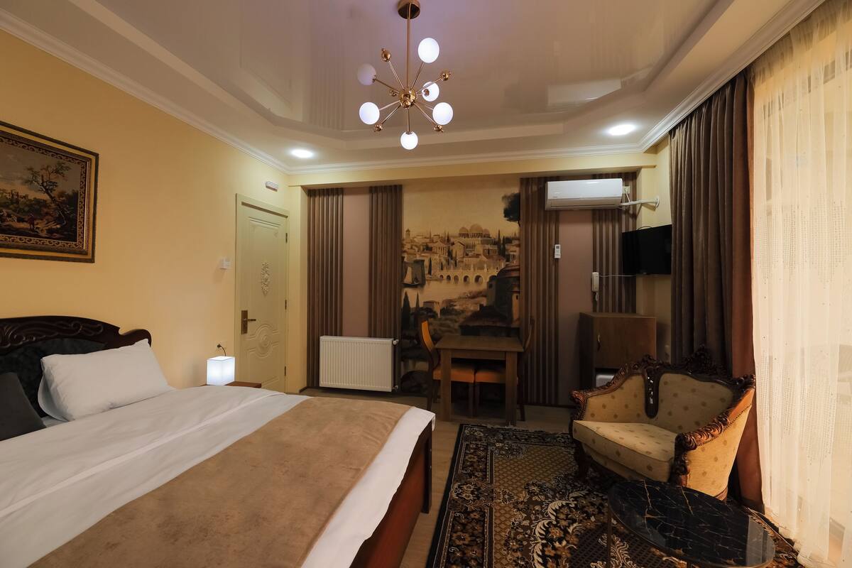 Ein Hotelzimmer mit einem großen Bett, einem Schreibtisch, einem Sessel und einem Fernseher.