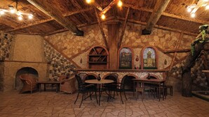 L’intérieur est rustique, avec des murs en pierre, des poutres en bois et un sol en pierre. On y trouve deux tables avec des chaises, une cheminée et une fresque murale.