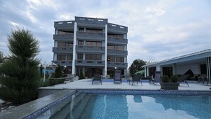 Un bâtiment moderne doté d’un espace piscine, comprenant une piscine et des chaises longues.