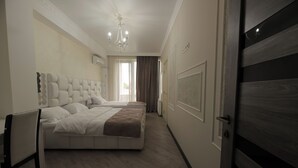 Une chambre à coucher avec un grand lit, une chaise, un lustre et une porte.