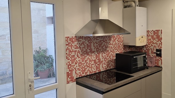 Una cocina moderna con una isla central, horno empotrado y ventana con vista a un patio.
