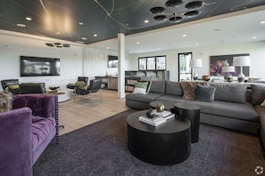 Un salon moderne avec un canapé gris, un fauteuil violet et une table basse noire.