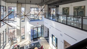 Un hall d’hôtel moderne, doté d’un plafond haut, de grandes fenêtres et d’une mezzanine.