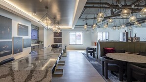 A modern kitchen with a long island, pendant lighting, and a dining area with a round table. - Parkside Chic 2BR Near Regions Field + Park (Birmingham)