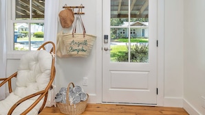 Une porte blanche avec un panneau de verre, un panier en osier contenant un sac en tissu tissé, et un autre panier en osier contenant des couvertures roulées.