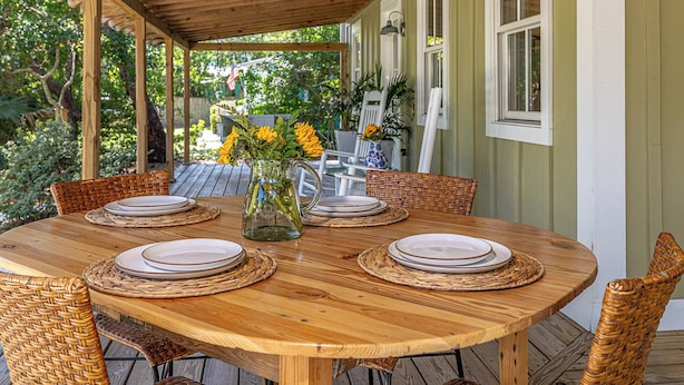 Une table en bois recouverte, avec six chaises, un vase rempli de fleurs jaunes et une carafe.