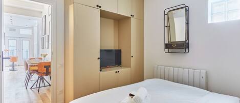 Une chambre d’hôtel équipée d’un lit, d’une télévision, d’un miroir et offrant une vue sur la salle à manger.