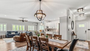 Amplia sala de estar con comedor, cocina y zona de estar con sofá y sillones.